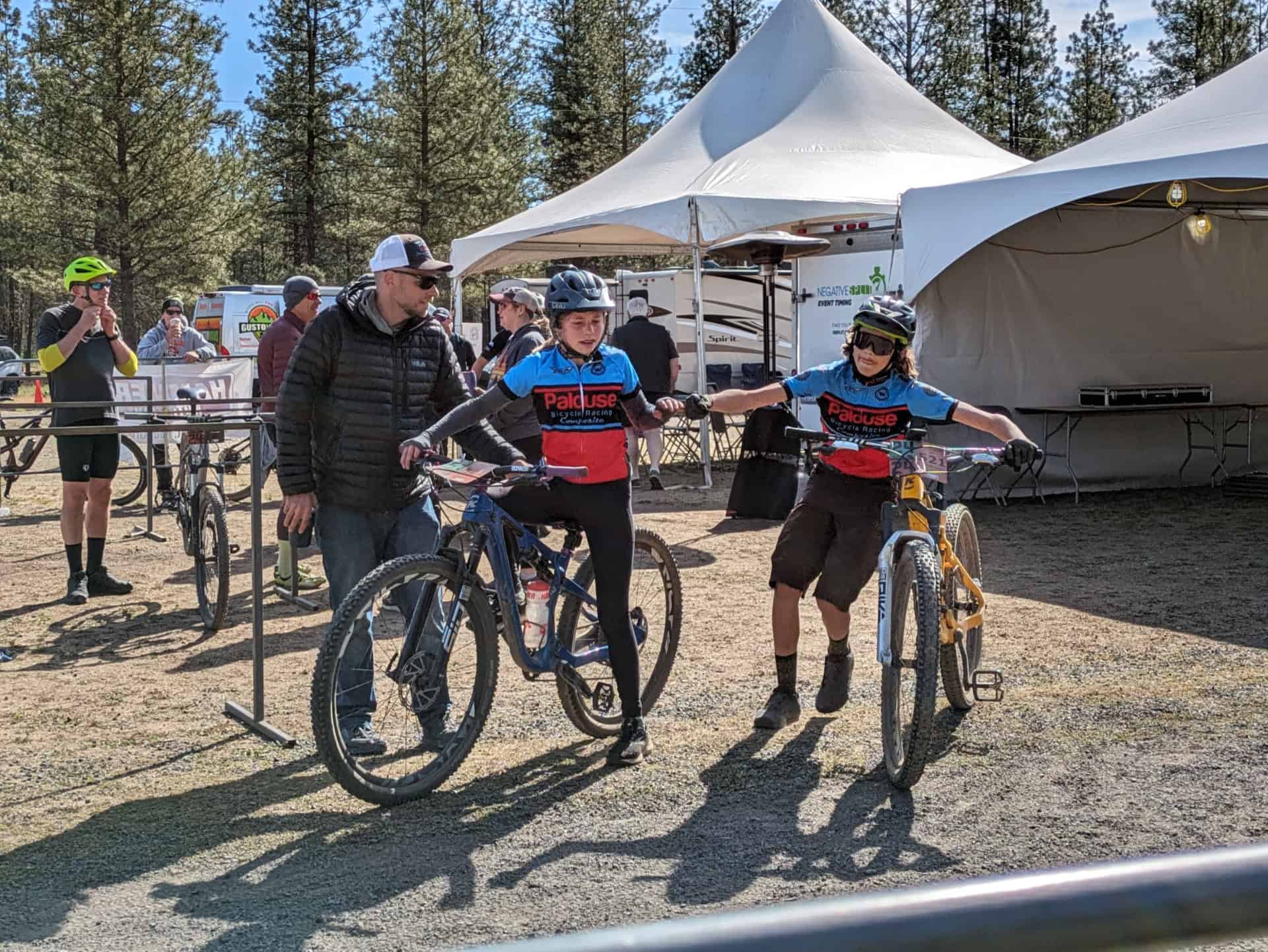 Two PBR cyclists tapping hands at relay race.